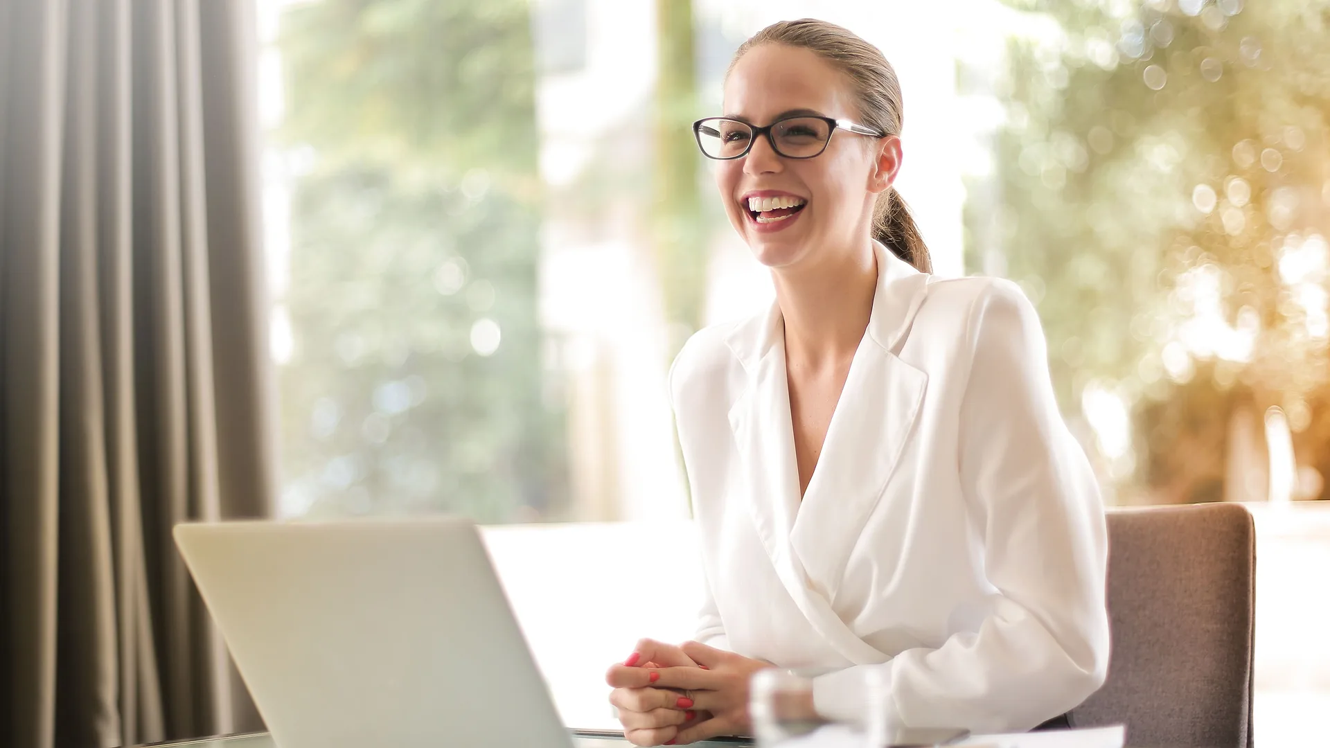Profissional de Departamento Pessoal sorrindo diante do notebook